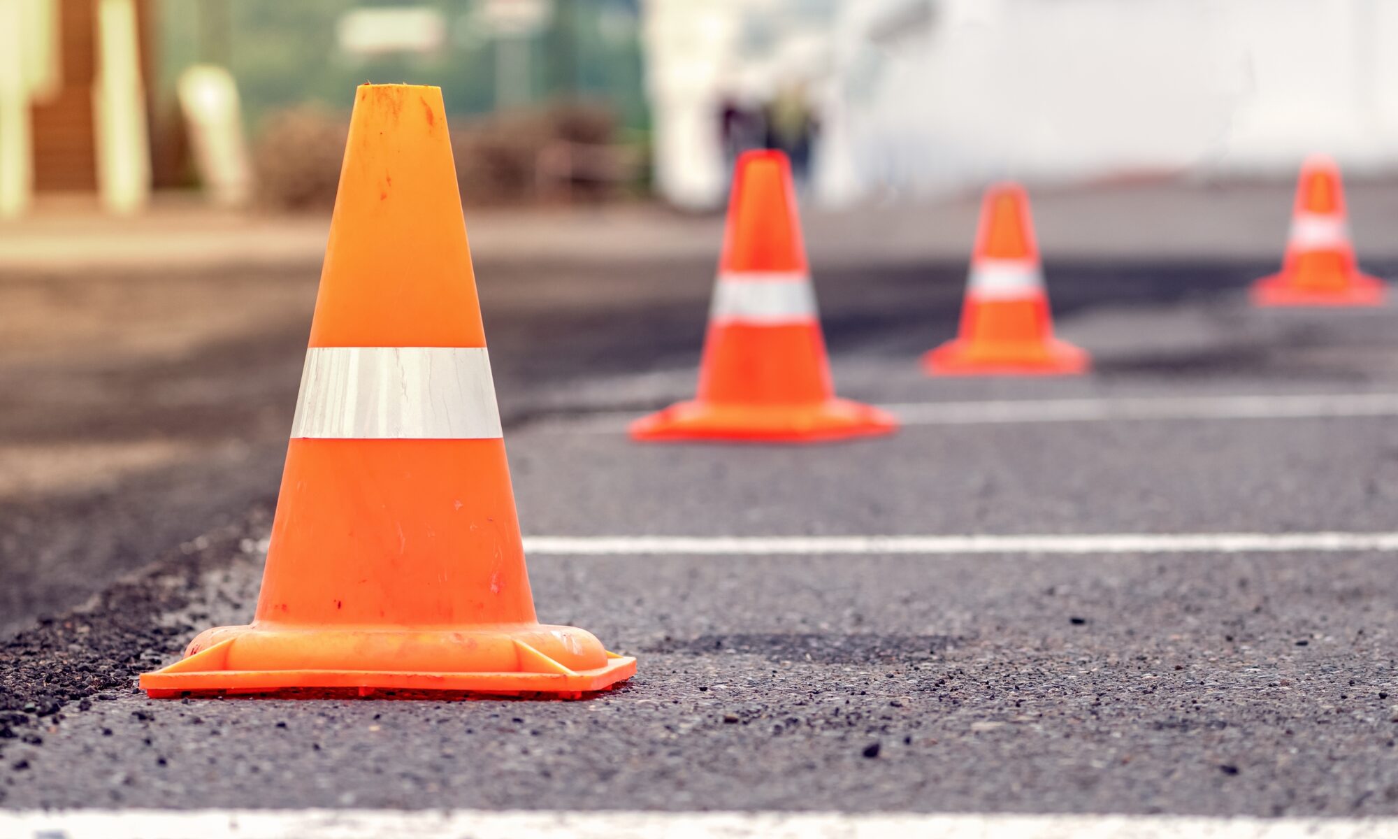 Rows of bright orange traffic cones placed on the asphalt road at a construction site road repairs